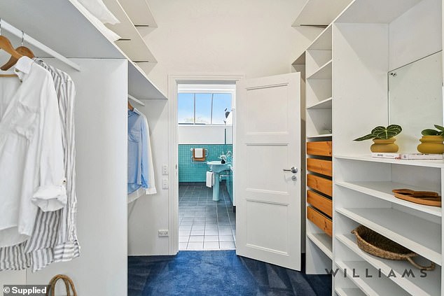 A spacious walk-in closet leads to the striking bathroom with aquamarine tiles