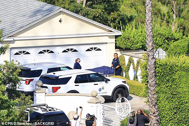 The coroner is seen removing the body of fitness guru Simmons from his LA home over the weekend