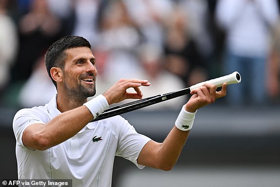 TOPSHOT - Novak Djokovic of Serbia imitates playing the violin with his racket as he celebrates his victory over Lorenzo Musetti of Italy during their men's tennis semi-final match on day 12 of the 2024 Wimbledon Championships at The All England Lawn Tennis and Croquet Club in Wimbledon, south-west London, on July 12, 2024. Djokovic won the match 6-4, 7-6, 6-4. (Photo by ANDREJ ISAKOVIC / AFP) / RESTRICTED TO EDITORIAL USE (Photo by ANDREJ ISAKOVIC/AFP via Getty Images)