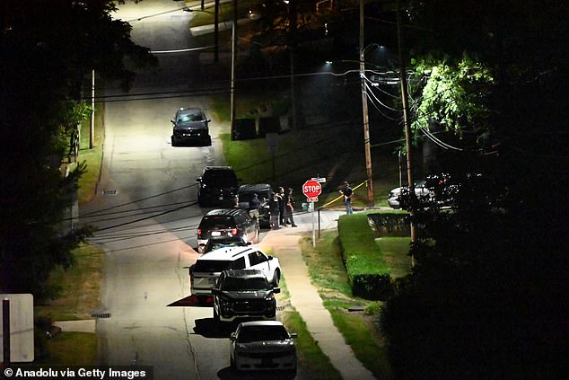 Officers stand guard outside a cordon in Bethel Park as officers search an address registered to Crooks