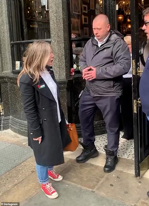 A guard stands at the door while the woman argues with the staff member