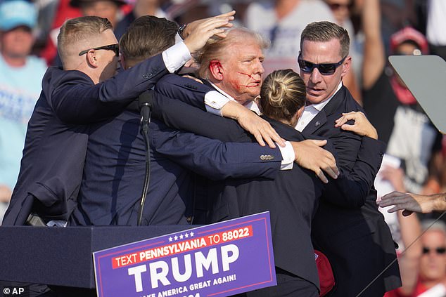 Former President Donald Trump is surrounded by Secret Service agents after a bullet hit his ear during an attempted assassination on Saturday in Butler, Pennsylvania