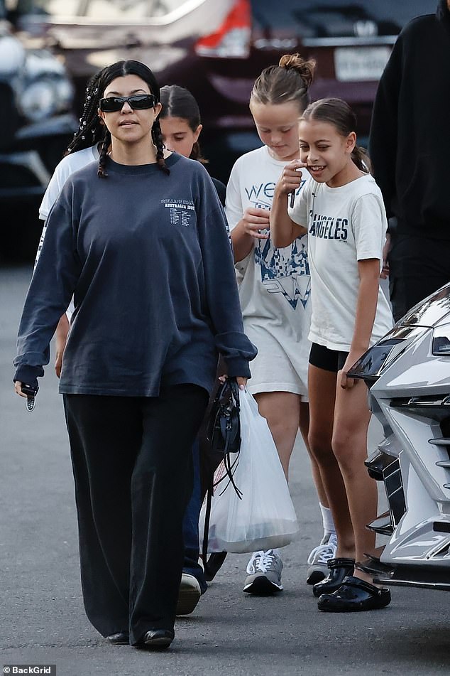 The 45-year-old mother of four borrowed her husband Travis Barker's long-sleeved navy shirt from the Rollins Band's 1992 Australian tour and paired it with wide-leg black trousers and matching ballet flats for their family dinner