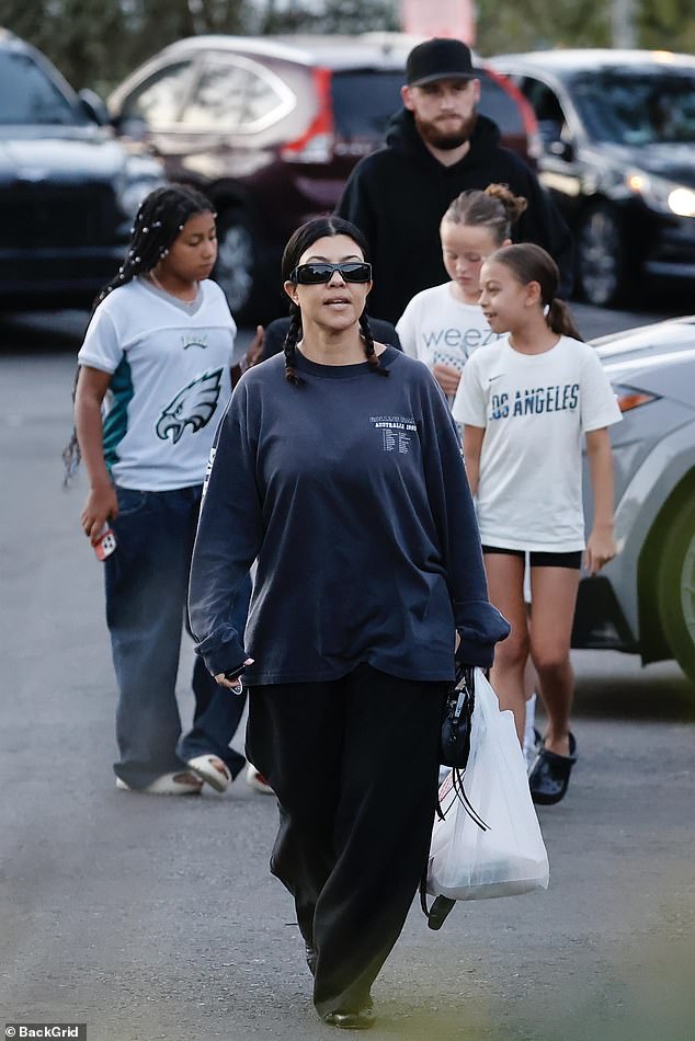 Kourtney - whose raven black hair was styled in braids - and her mini squad were accompanied by a black-clad, bearded bodyguard, who towered over all five