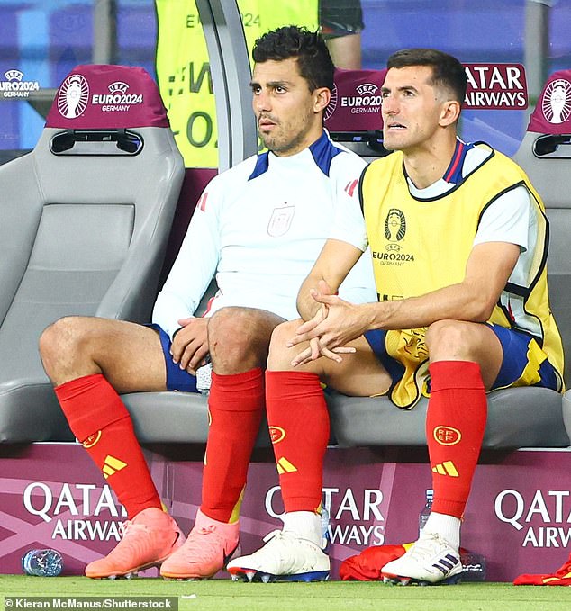 Rodri (left) takes his place on the Spanish bench after being substituted at half-time