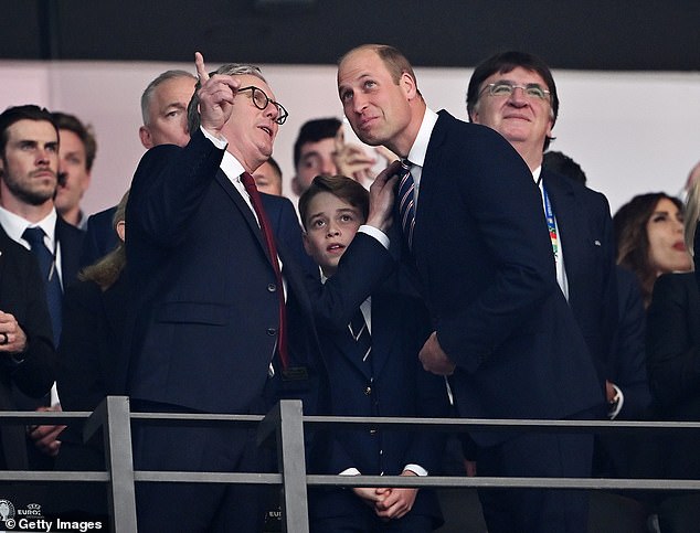 Prime Minister Keir Starmer places his hand on Prince William's shoulder as he points to something in the stadium