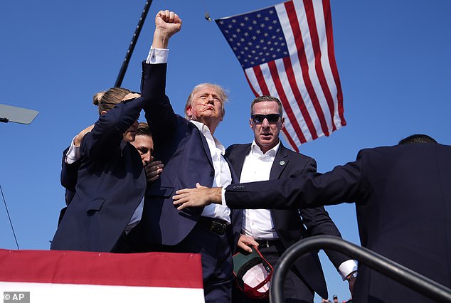 Trump raises his fist under the American flag, blood streaming down his face, moments after the shooting