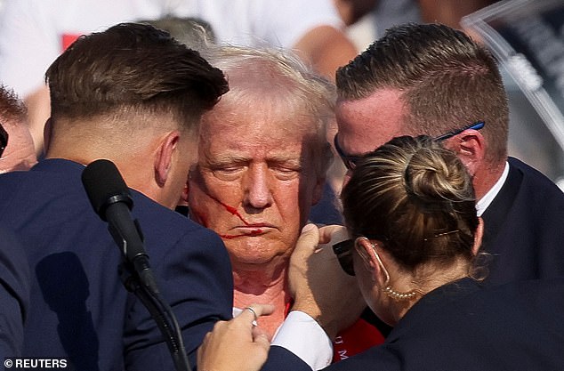 Trump is surrounded by Secret Service agents in the moments after the shooting, raising his fist to indicate he was OK in an image that has since gone viral