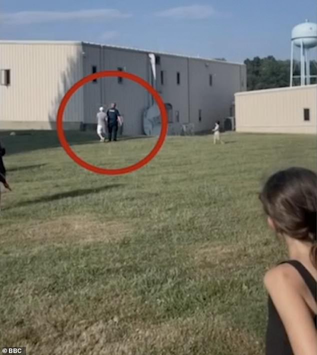 A member of the public can be seen talking to a police officer before the shots rang out, the building where Crooks was sitting is on the right