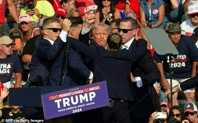 Republican candidate Donald Trump is surrounded by Secret Service agents with blood on his face as he is escorted off stage at a campaign rally