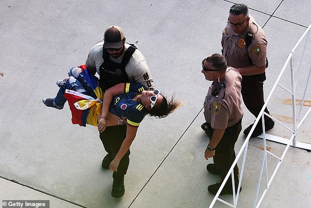 A police officer carries an unconscious fan outside Hard Rock Stadium in Miami