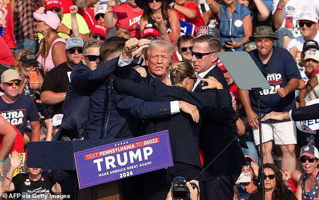 Donald Trump is seen with blood on his face as he is surrounded by Secret Service agents who attempt on his life during a campaign rally in Butler, Pennsylvania