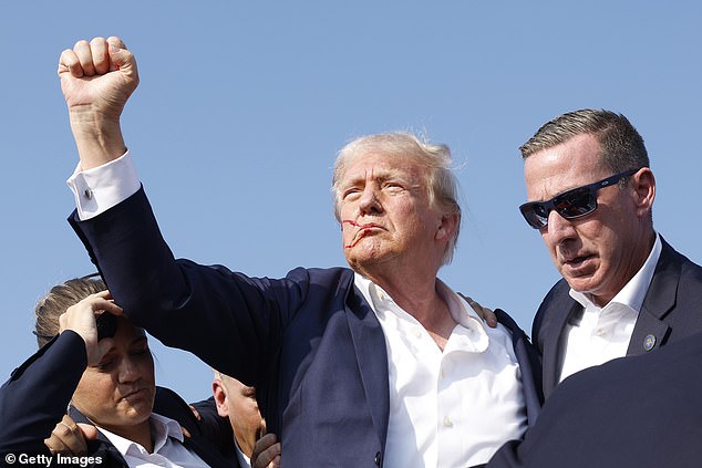 Trump manages to hold up a clenched fist after getting back to his feet after the shooting