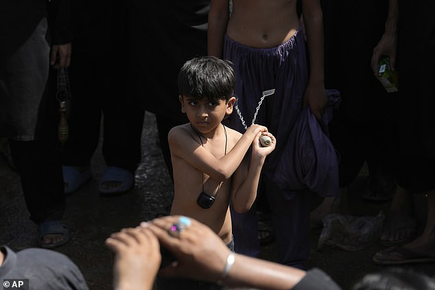 A Shiite Muslim boy holds a knife attached to chains during a Muharram procession in Islamabad, Pakistan today