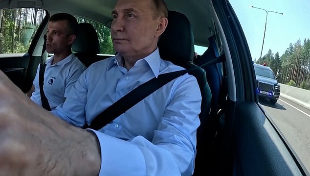 Footage from inside the vehicle shows Putin driving along the highway wearing a white shirt with the top button open