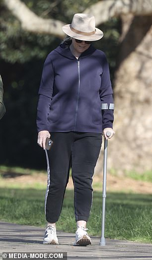 Samantha leaned on a metal crutch for support as she walked through the park