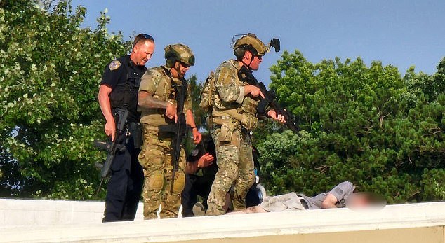 Police officers stand on a roof near the body of Thomas Matthews Crooks on Saturday, near the Trump rally