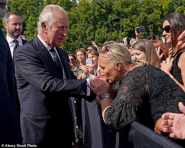 A royal fan kisses King Charles' hand during a walk outside Buckingham Palace following the death of his mother Queen Elizabeth, September 2022