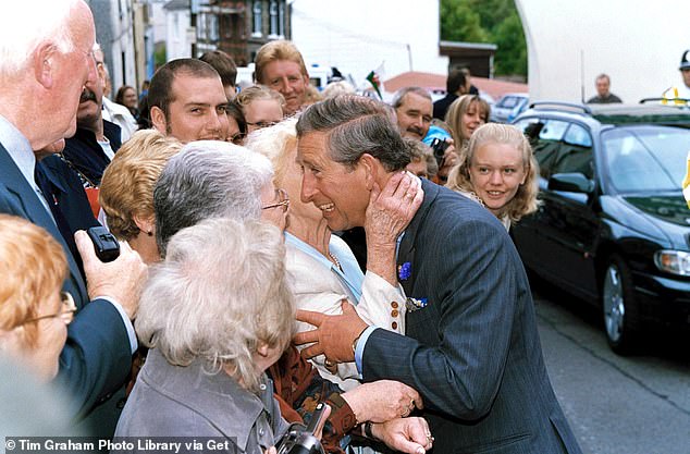 Prince Charles is kissed by an older woman during a visit to Cwmaman, in Aberdare, Wales, in 2001