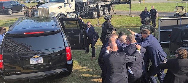 Without any other form of head protection, an officer was seen shielding the politician's head with only his bare hand moments after he was shot in the ear