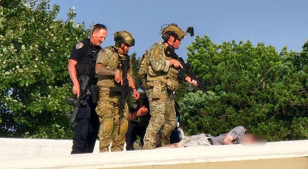 Police officers stand on a roof near the body of Thomas Matthews Crooks on Saturday, near the Trump rally