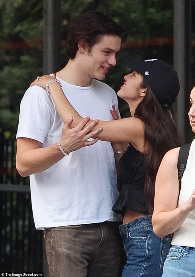 Olivia, dressed in a New York Yankees baseball cap, a black pleated tank top and jeans, couldn't keep her red-manicured hands off her boyfriend.