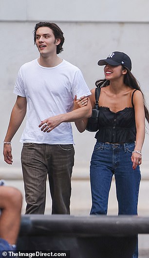 Olivia held onto her boyfriend's arm as they walked through the city laughing and chatting