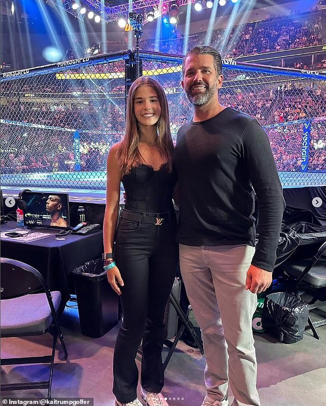 Kai stands front row at the high-profile event with her father, wearing a trendy all-black outfit consisting of a lace black corset top, a Louis Vuitton belt and a blue embellished bag.