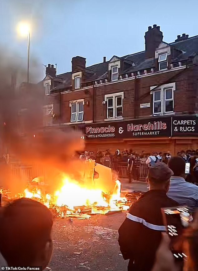 Locals watch a bonfire on the street in Harehills, Leeds. Police have urged locals to disperse