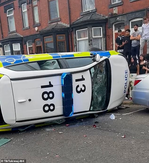 A police car was blown over as chaos broke out on the street in Harehills, Leeds