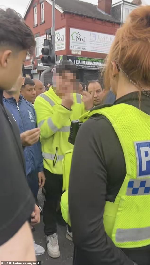 A man makes an insulting gesture towards a police officer. West Yorkshire Police have sent dozens of officers to the scene and closed roads