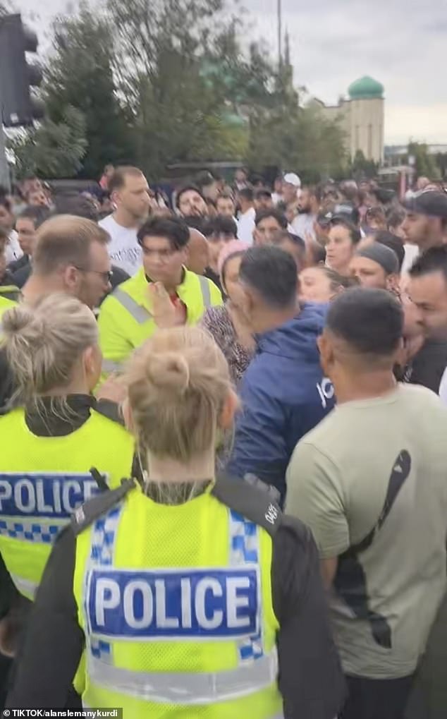 Police officers deal with the large crowd of people gathered at the scene of the accident