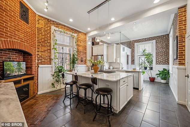 The kitchen looks like it came straight out of a cooking show with its floor-to-ceiling brick walls, modern tiled floors and marble cooking islands with white cabinets