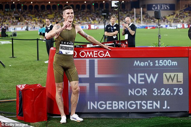 Ingebrigtsen poses for a photo next to the LED board showing his world best time