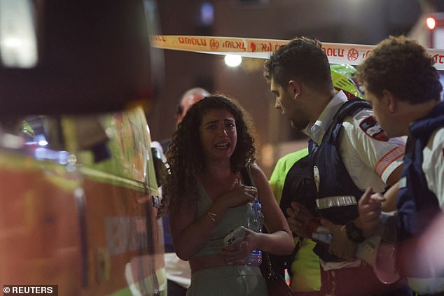 Emergency workers assist a woman at the scene of the explosion in Tel Aviv