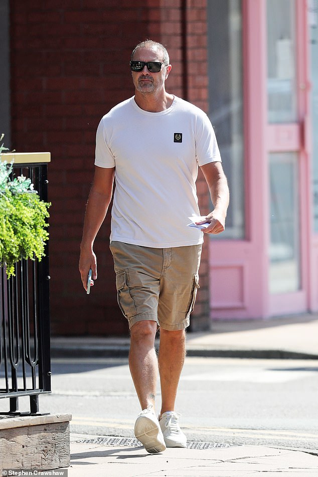 He wore a casual look in a white T-shirt and beige swimming trunks