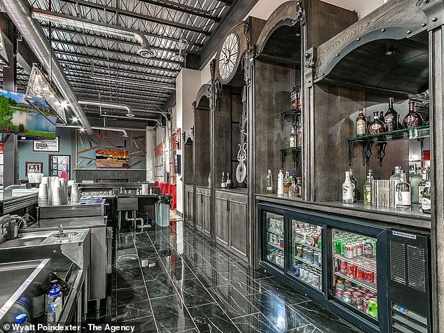 Pictured: One of the kitchens, featuring a futuristic black and white design with a silver backsplash, black cabinets and white marble countertops