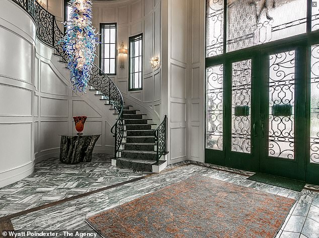 The front hall features an interesting blue chandelier and a spiral staircase