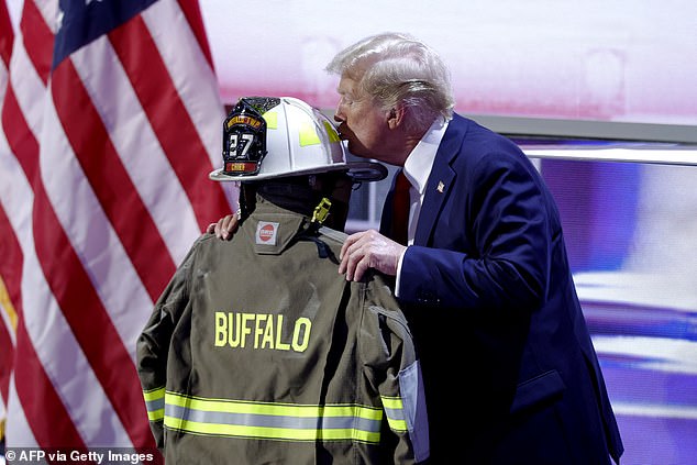 Trump kisses a helmet and firefighter's jacket that belonged to Corey Comperatore, who was fatally shot at a rally where Trump survived an assassination attempt, as he accepts his party's nomination on the final day of the 2024 Republican National Convention