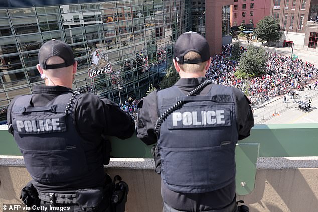 Police monitor the scene outside the Van Andel Arena in Grand Rapids from the roof of another building