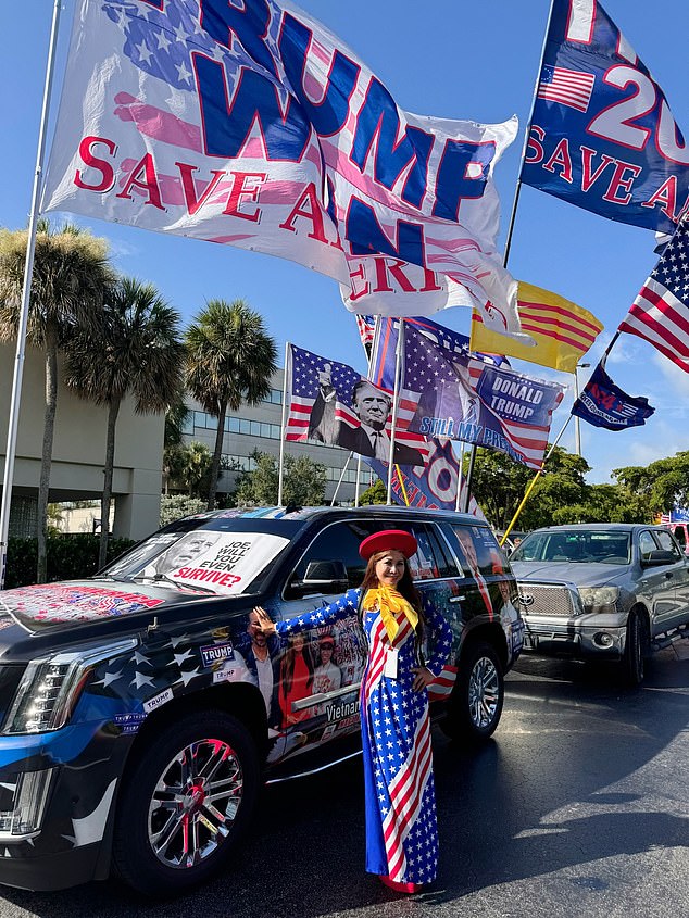 A Trump fan poses next to an SUV decorated with political messages and flags on the back