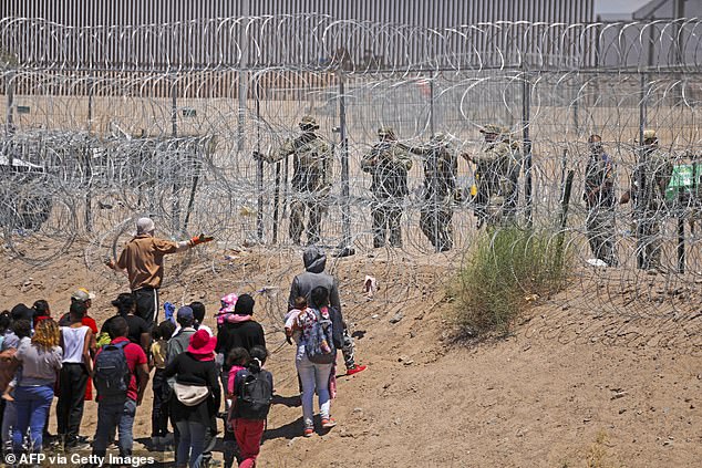 Migrants attempting to enter the United States through a barbed wire fence along the Rio Grande are repelled with pepper spray by Texas National Guard officers at the border with Ciudad Juarez, Chihuahua state, Mexico, on May 13.