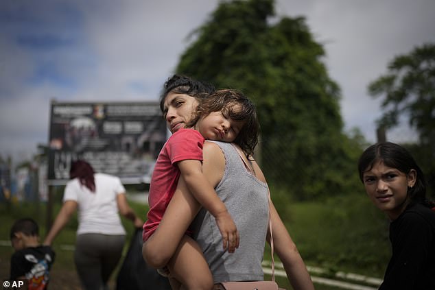 Venezuelan migrant Naiber Zerpa holds her son Mathias Marquez as they arrive at a temporary camp after crossing the Darien Gap from Colombia