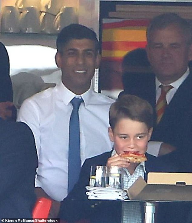 Prince George enjoys a large slice of pizza as his father speaks to then Prime Minister Rishi Sunak during the England v Australia cricket match during the Ashes last year