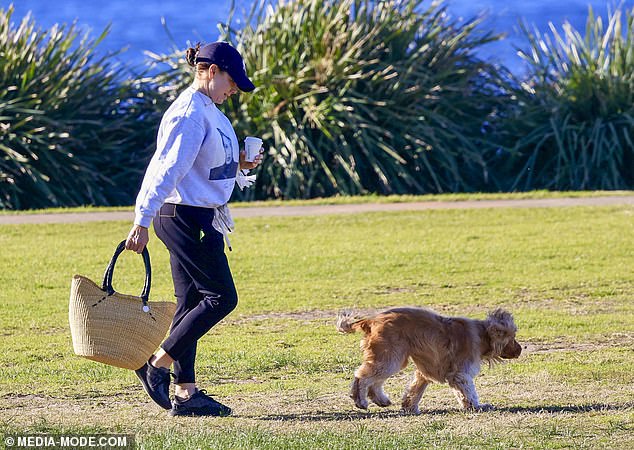 The actress kept warm in a gray sweater and black sweatpants as she enjoyed a cup of coffee while her dog ran through the park