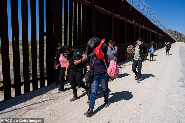 Migrants walk along the border fence after crossing from Mexico into the U.S. in Jacumba Hot Springs, California, on June 14, 2024