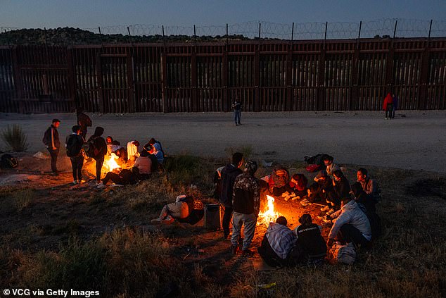 Migrants sit by fires to warm up as they wait for U.S. Border Patrol agents to pick them up and process them