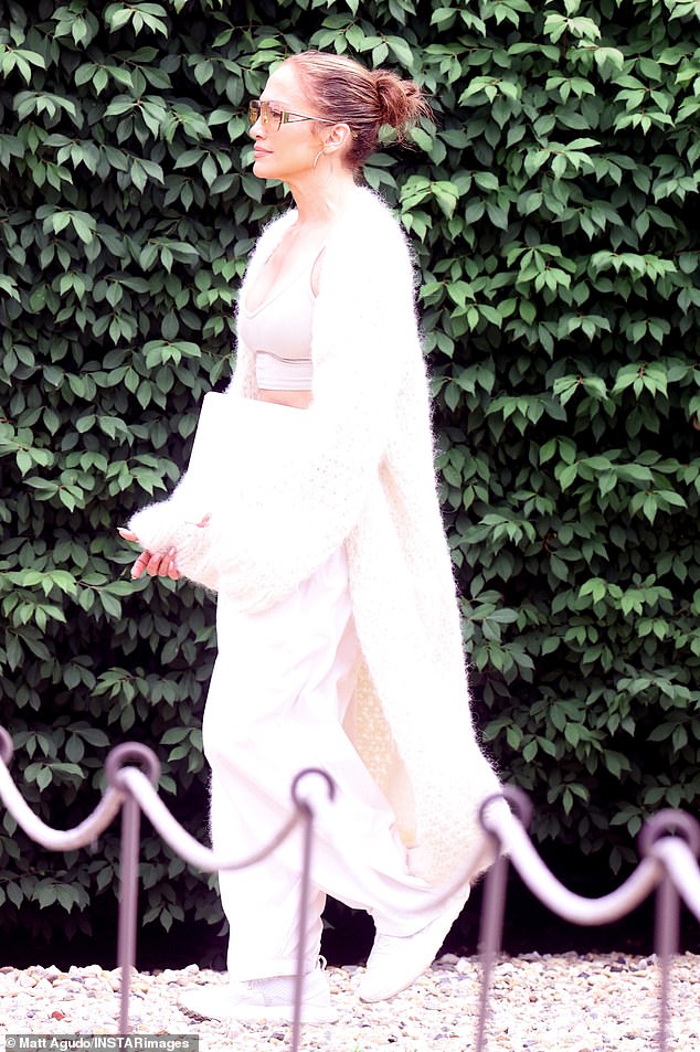 The actress and singer wore a light pink sports bra and matching pants and appeared to hide her wedding ring finger under the oversized sleeves of her furry white designer dress