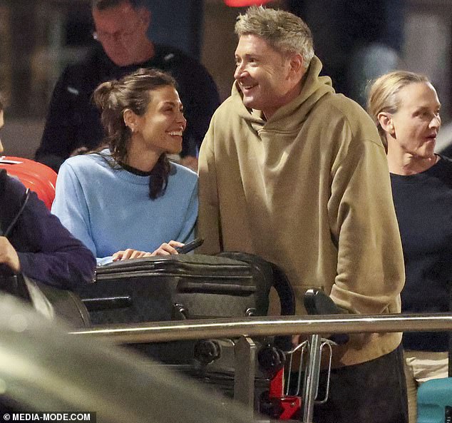 They were all smiles as they arrived home, with Arabella, 32, cuddling up to the former cricket captain as he pushed their four suitcases