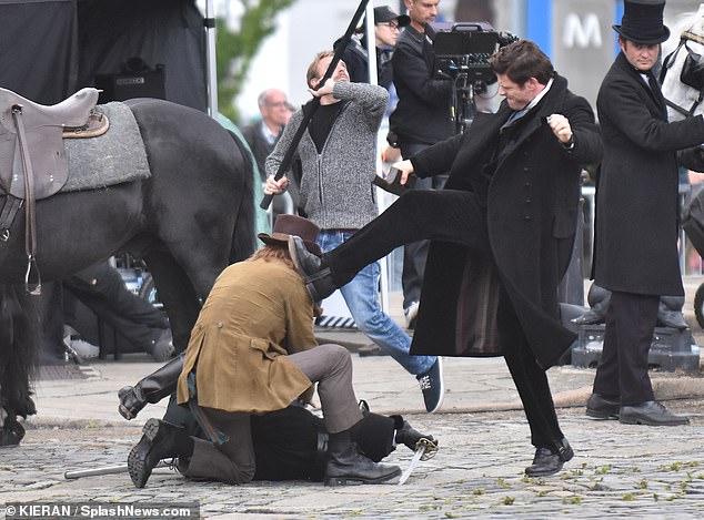 James looked furious as he was caught with a piece of metal in his hand as he waved his arm in the air before kicking his co-star who was lying in the road